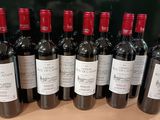 des bouteilles de vin rouge alignées sur une table devant un tableau noir