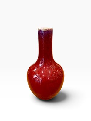 un vase rouge posé sur une surface blanche