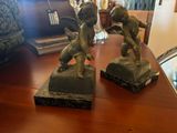 two statues on a table with a mirror in the background