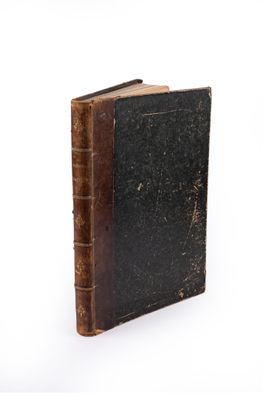 an old book that is sitting on a white surface