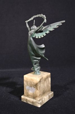 une statue en bronze représentant une femme ailée, posée sur un socle en marbre