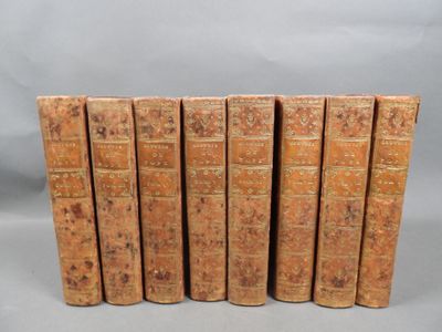 six old books are lined up in a row on a gray background