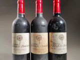 three bottles of red wine are lined up on a table