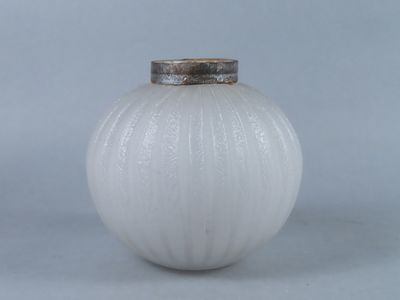 un vase blanc avec un couvercle argenté posé sur une table