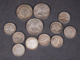 Plusieurs pièces de monnaie différentes sont disposées en cercle sur une surface noire