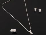 un collier, des boucles d'oreilles et une bague en argent, présentés sur un fond noir