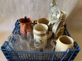 un panier bleu rempli de tasses et de pichets posé sur une table