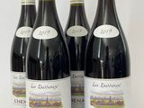 quatre bouteilles de vin rouge sont alignées sur une surface blanche