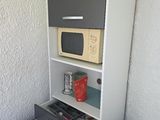 une petite armoire sur laquelle est posé un micro-ondes, à côté des toilettes