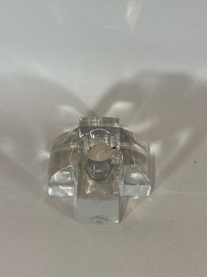 a clear glass object on a white surface with a shadow