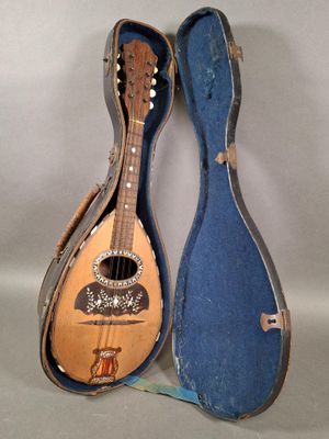 un vieil étui à guitare contenant une guitare, posé sur une surface blanche