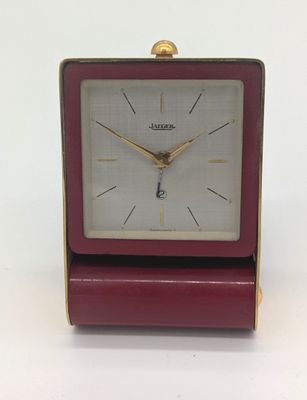 une petite horloge rouge posée sur une table blanche