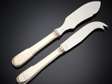 a pair of silverplated cheese knives on a black surface