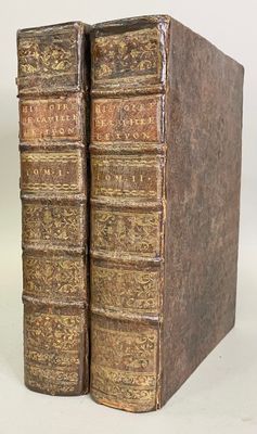 two old books sitting on top of each other on a white surface