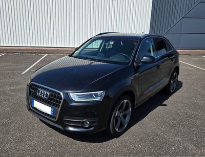 L'Audi Q3 est garée sur un parking près d'un immeuble.