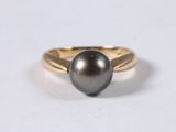 a close up of a black pearl ring on a white surface