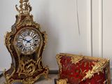 trois horloges posées sur une table, à côté d'un sac à main et d'une horloge