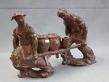 two figurines of a man and a woman pulling a wagon