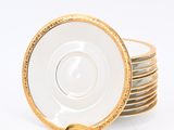 four gold and white cups and saucers on a white background