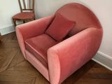 a pink chair with a pillow on it in a room