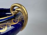 a blue vase with a gold decoration on it
