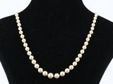 a white pearl necklace on a black mannequin