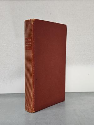 un livre brun posé sur une table à côté d'un mur blanc