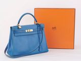 a blue handbag next to an orange box on a white surface