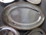 many silver plates on a black table with silver lids
