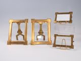 three gold frames with a mirror on top of them on a white surface