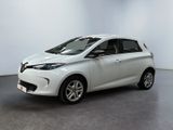 La voiture blanche est garée dans une pièce au sol gris.