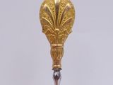 an image of a gold and silver spoon on a white surface