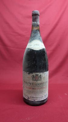 an old bottle of wine sitting on a red surface