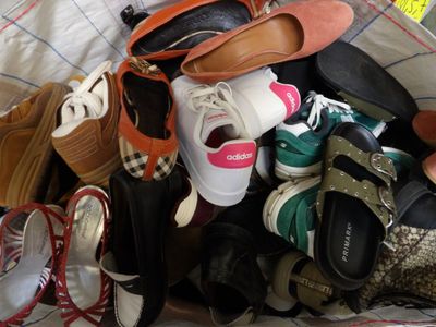 many pairs of shoes sitting in a pile on a bed