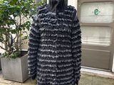 un manteau noir à volants posé sur un mannequin devant une plante en pot