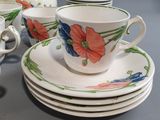 four cups and saucers on a table with a tea kettle
