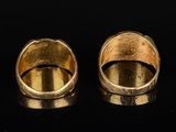 two gold rings on a black surface with a black background