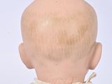a small doll with a bald head and a white shirt