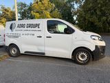 two white vans parked in a parking lot with trees in the background