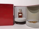 a red box with a bottle of perfume and a gold ring in it