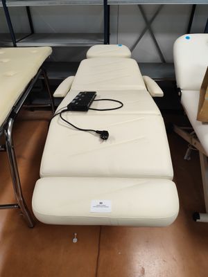 une table de massage blanche sur laquelle se trouve une télécommande