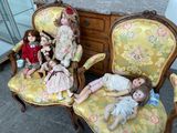 many dolls sitting on the chairs in the room
