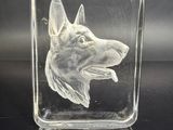 bloc de cristal sur lequel est gravée une tête de chien, sur un fond noir