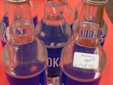 Six bouteilles de vodka sont alignées sur une table rouge.