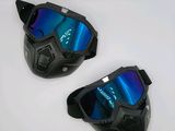 une paire de lunettes de protection noires aux verres miroités bleus posée sur une surface blanche