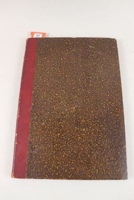 un livre marron et rouge posé sur une table blanche