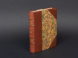 an old book with a brown cover sitting on top of a black surface