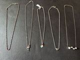 un ensemble de quatre colliers posés sur une surface noire
