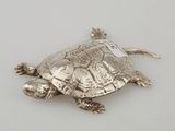 a silver turtle that is sitting on a white surface