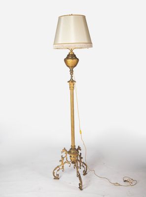 un lampadaire ancien en laiton surmonté d'un abat-jour blanc